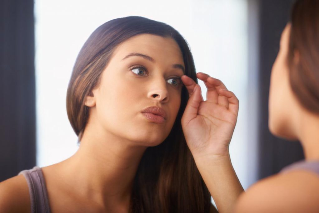 Wanita yang memandang cermin tertanya-tanya jika bulu mata tumbuh semula