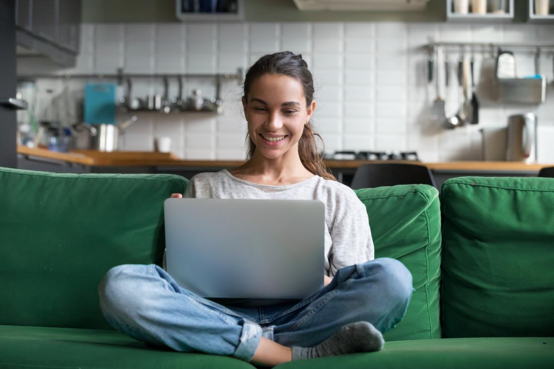 wanita mengakses dunia dalam talian dengan komputer riba di pangkuannya